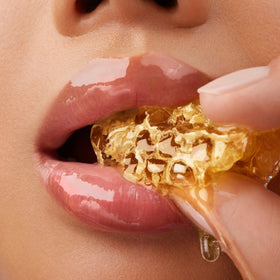 Close up of a mouth eating honeycomb.