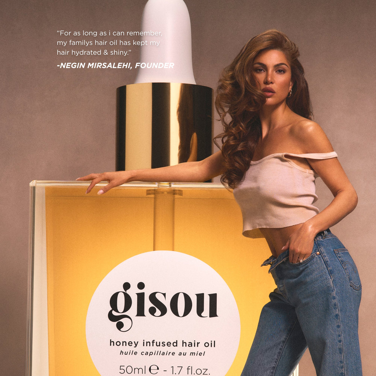 Negin Mirsalehi standing next to a life-size hair oil bottle.